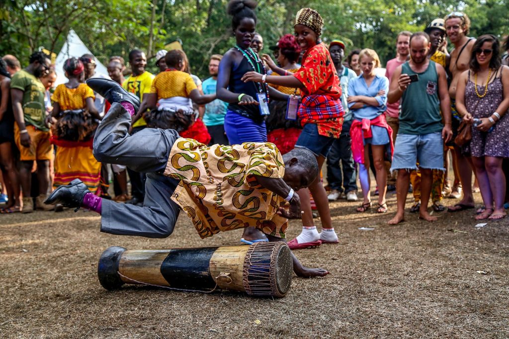 A traditional drummer performing for a joyful crowd