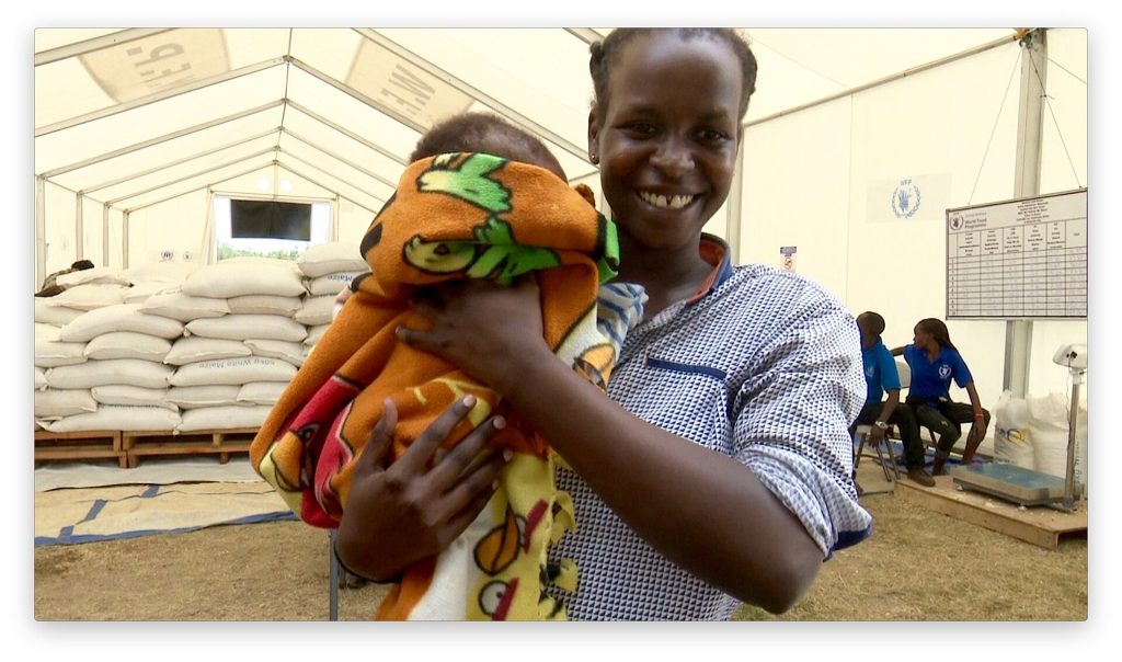 A smiling mother holding her baby at a relief centre